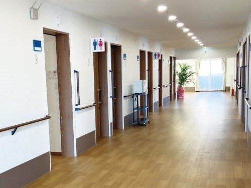 まっすぐな廊下は幅が広く、両サイドに手すりと居室のドアが並んでいて、トイレも設置されている。