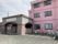 ピンクの３階建ての建物が右側にあり、左側にはブラウンの平屋建ての建物がある。