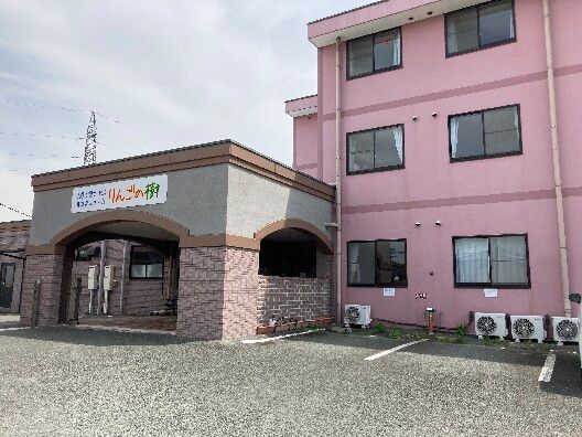 広い敷地内にはピンクの3階建ての建物とブラウン系の平屋建ての建物があり、日当たりのいい場所に建っている。