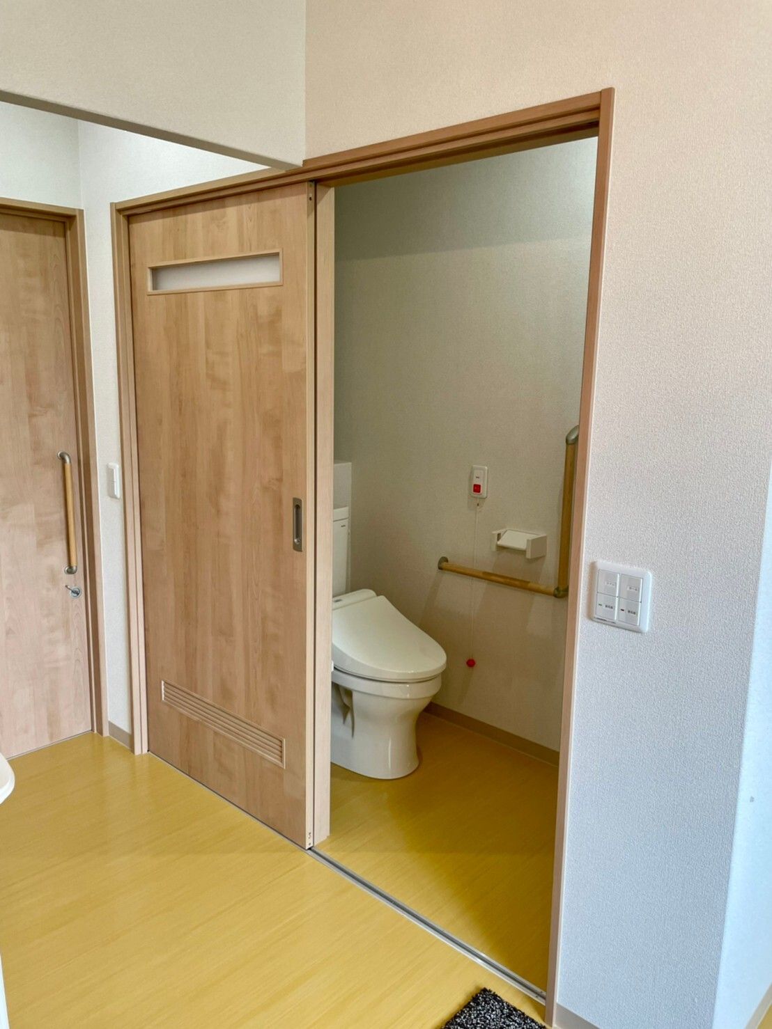 引き戸仕様の居室内のトイレの様子。緊急コールと手すりがついた介護用のトイレ