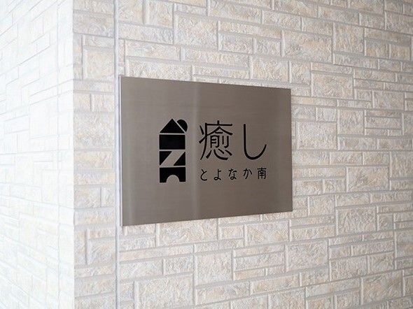 レンガ調の外壁にシルバーのプレートが貼られ、住宅名が黒文字で書かれている。
