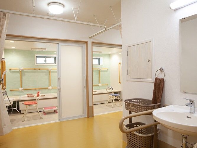 広い脱衣所に一人用の浴室が二つあり、カーテンで仕切ることができる。洗面所もあり、手すりが付いている。