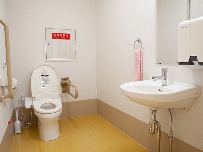 広いトイレには呼び出しボタンも設置され、手洗い場も完備。手すりも可動式・固定式のものが両方ついている。