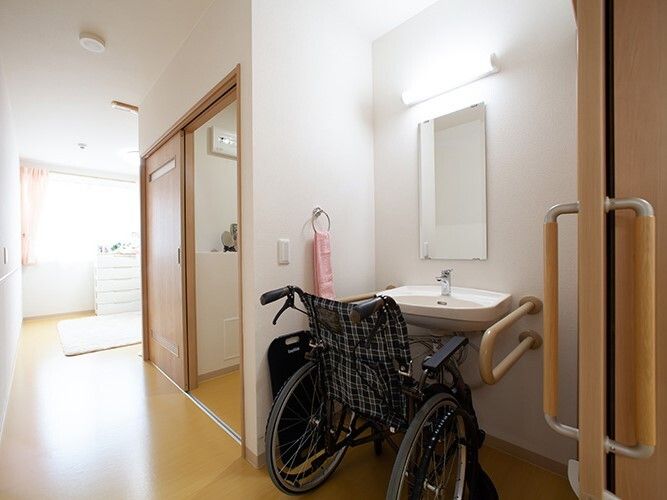 洗面所には車いすがセットされ、通路の向こう側にはリビングスペースが広がっている。トイレは引き戸。