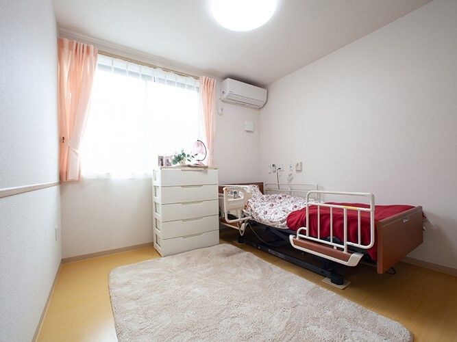 エアコン付きのフローリングの部屋には寝具付きのベッドやカーペット、タンスなどがある。