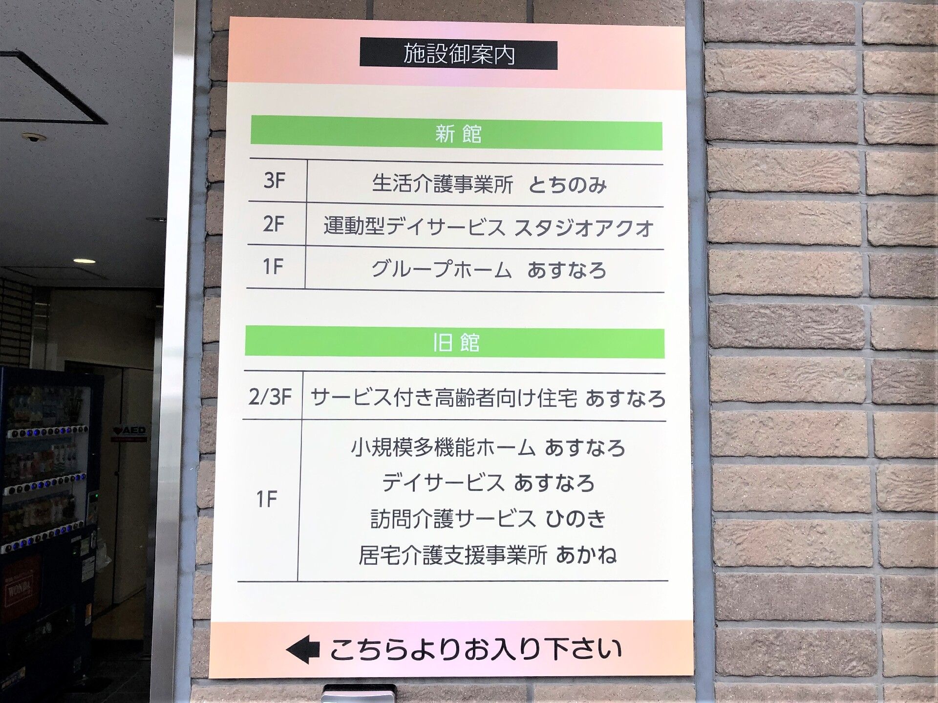 外壁には建物内にある事業所が書かれた案内版が貼られている。サービス付き高齢者向け住宅の他にもデイサービスやグループホームなどがある。