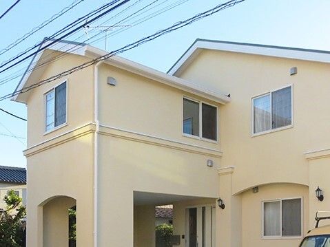 ベージュの建物は2階建てで建物の前には車が止まり、三角の屋根が一般の住宅のような雰囲気。