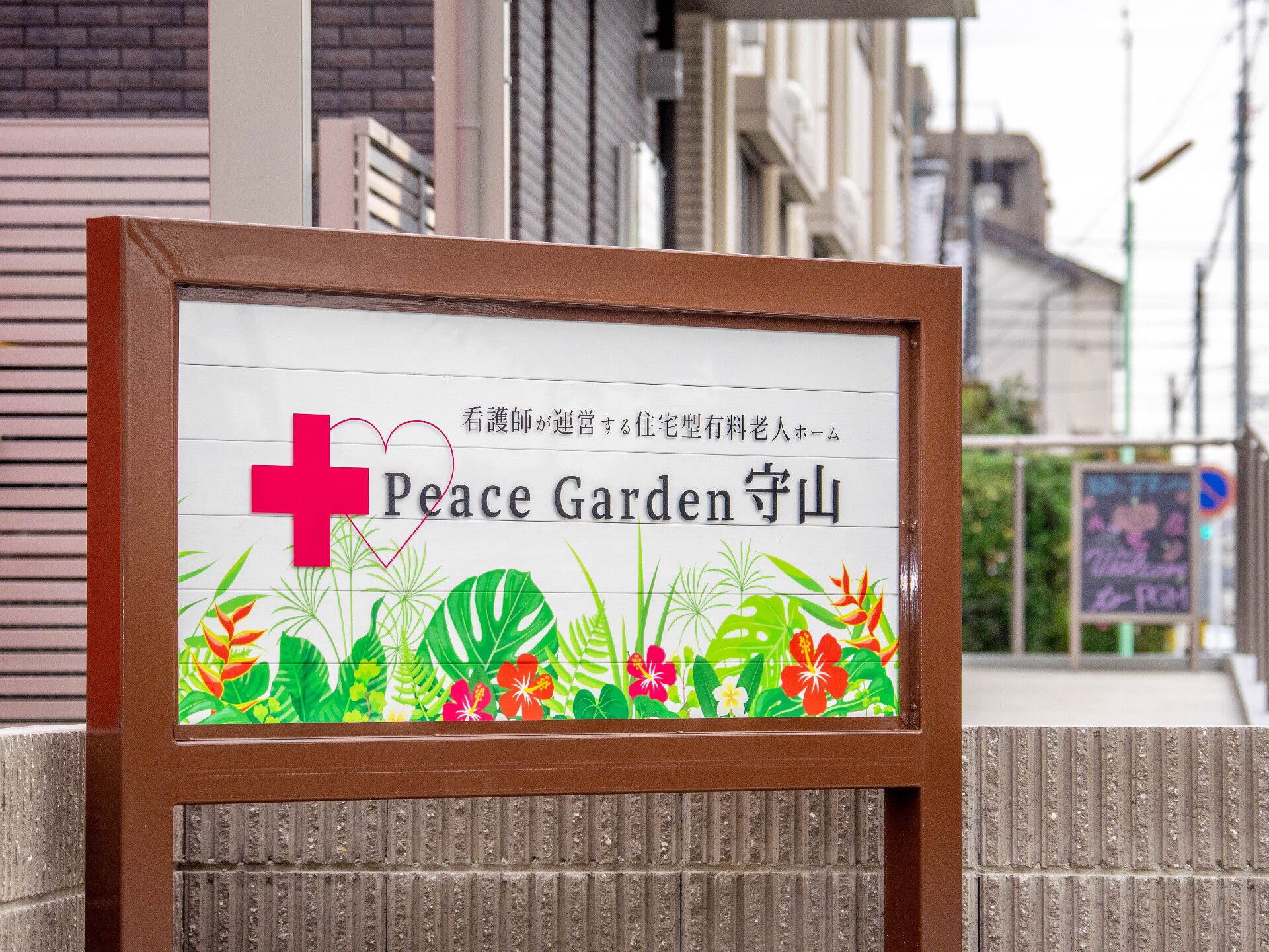 ホームの前にはある看板にはホーム名が書かれ、赤十字やカラフルな花のイラストが描かれている。