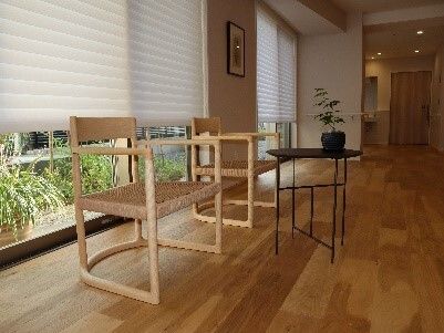 若い女性スタッフと高齢夫婦が並んで日当たりのいい芝生に座り、談笑している。