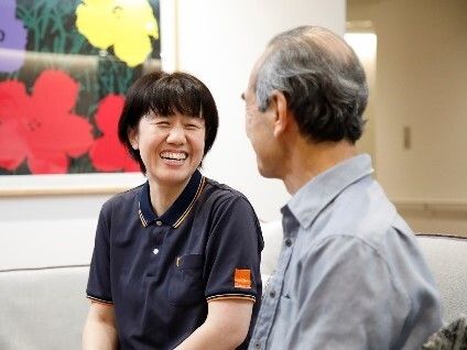 大きな花のアートが飾られた部屋で朗らかな表情で会話する男女