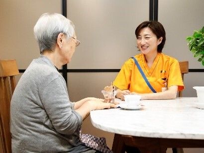 丸テーブル席に座り、お茶を飲みながら話をしている女性とスタッフ