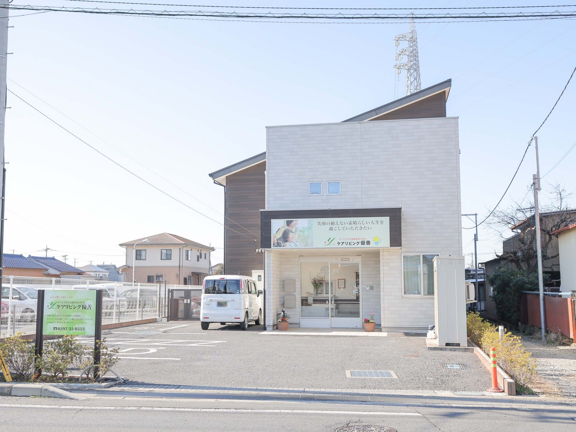 なにかを見て笑顔で手をたたいている高齢女性とスタッフの様子。施設での一場面の写真