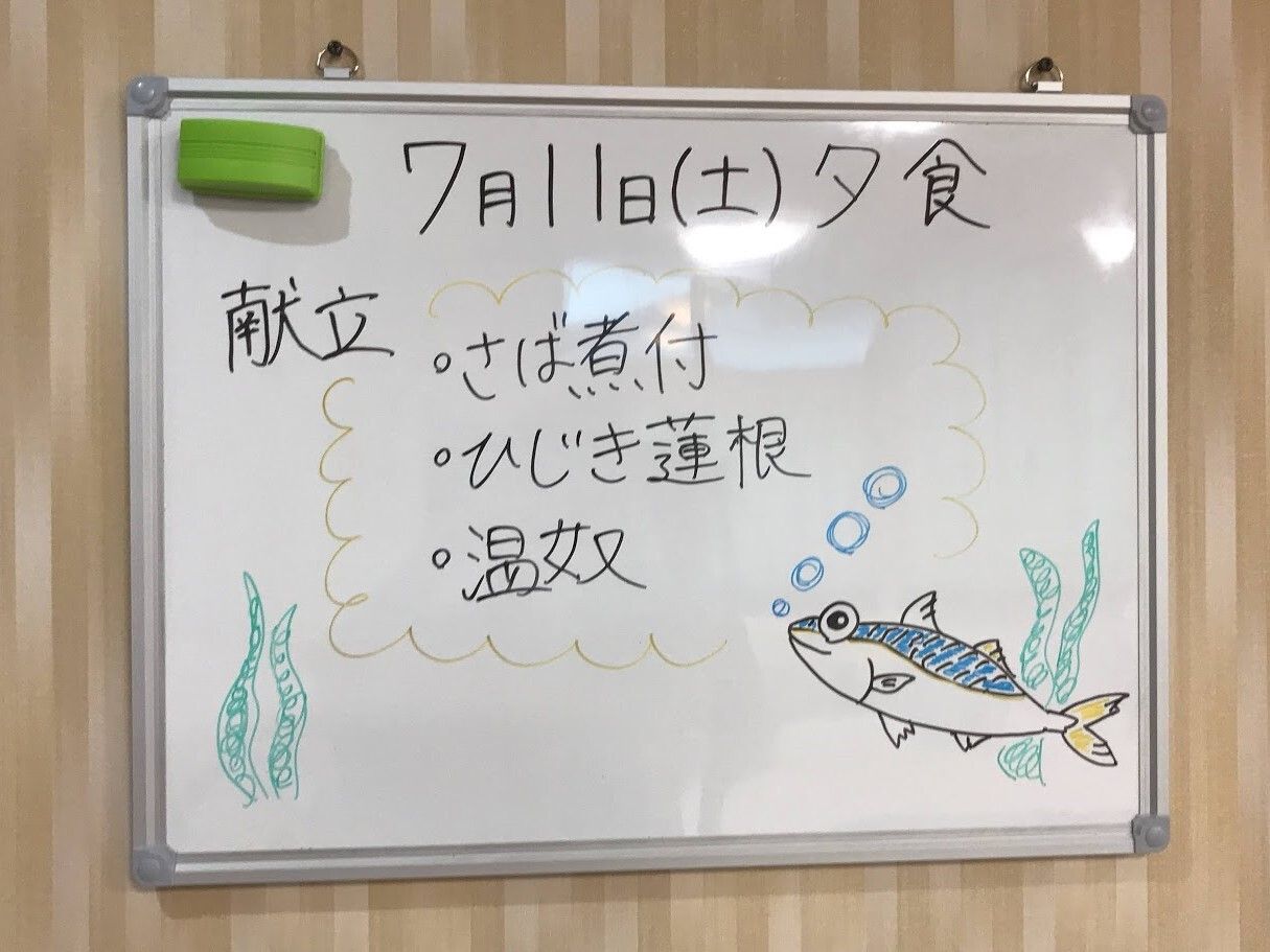 魚のイラストと夕食の献立が書かれたホワイトボード