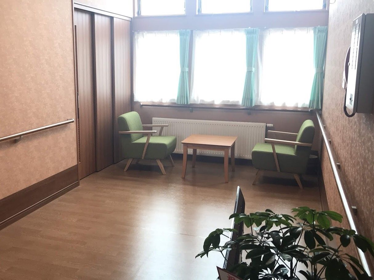 壁に手すりが設置され窓際にテーブルセットが配置された休憩スペース