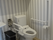 両サイドに手すりが付いたトイレは介助スペースも十分あり、トイレの上には棚も付いている。