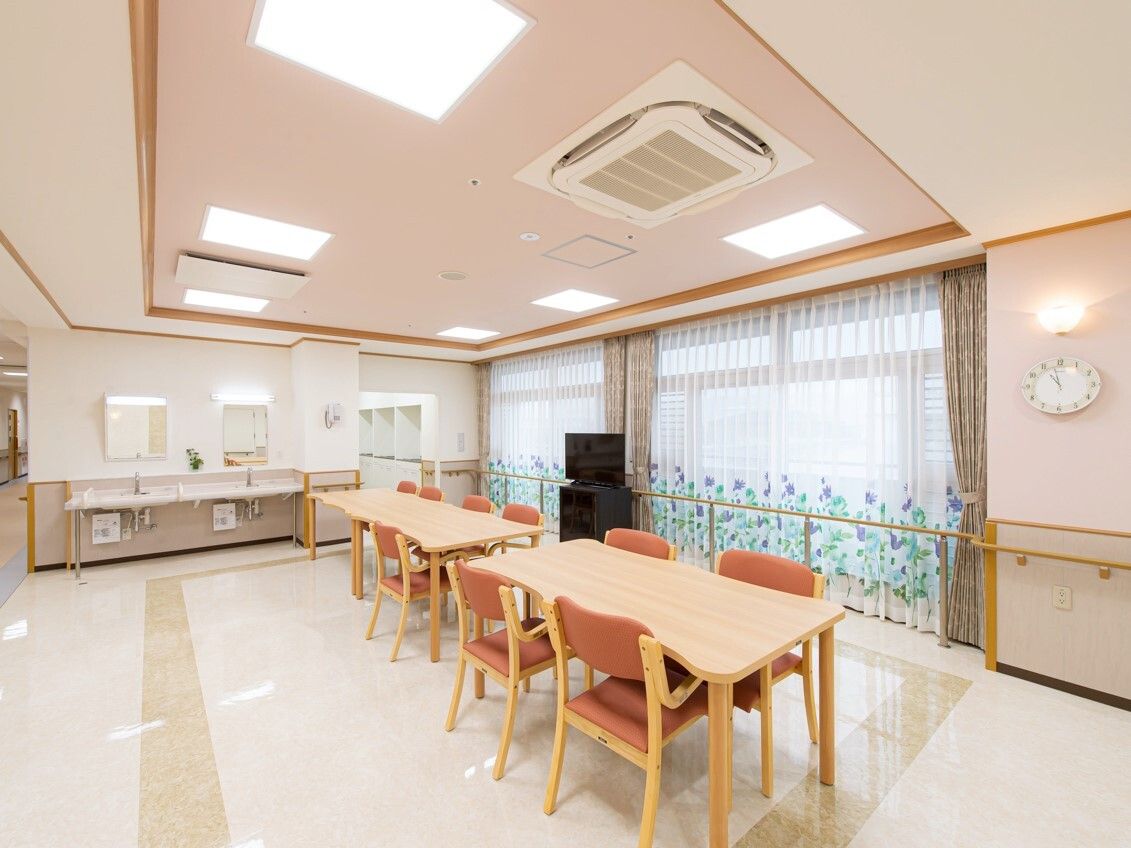 手すりが全域に設置された館内。共有部にはソファやテーブルが設置され、カーテンが付いたおおきな窓がある。