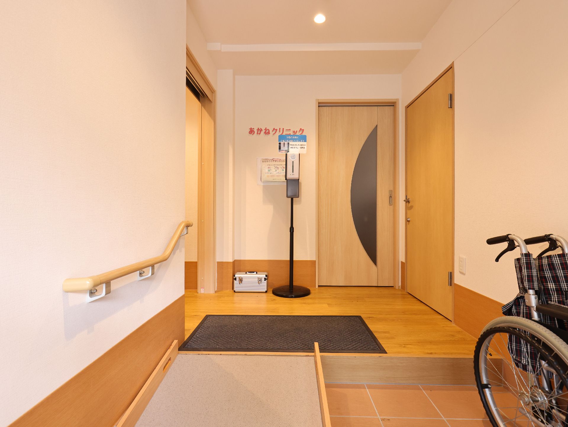 緑の多い屋外で笑顔で散歩をしている車いすの高齢女性と付き添いの若い女性スタッフ。