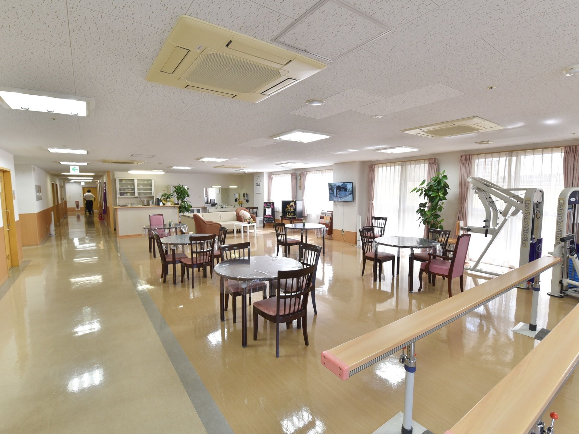 廊下からバリアフリーで広がるスペースの食堂である。丸テーブルにビニールクロスが掛けられている。椅子が配備され数セット設置されている。