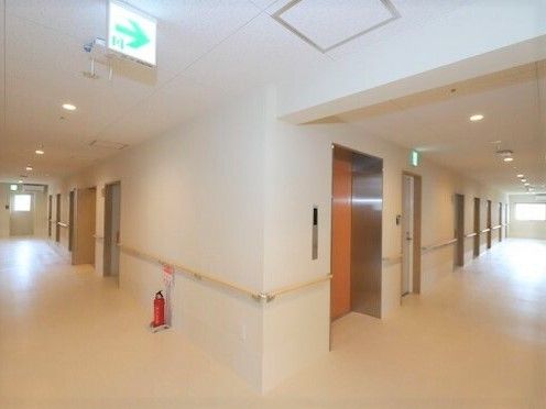 手すりが付いた廊下が両サイドに伸びていて、エレベーターや消火器も設置されている。