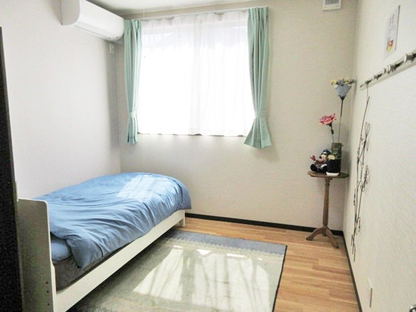 フローリングの部屋にはエアコンや寝具付きのベッドがあり、窓も付いていて明るい。