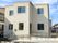グレーがかかった白の２階建ての建物。玄関には手すりつきの階段とスロープが設置されている。