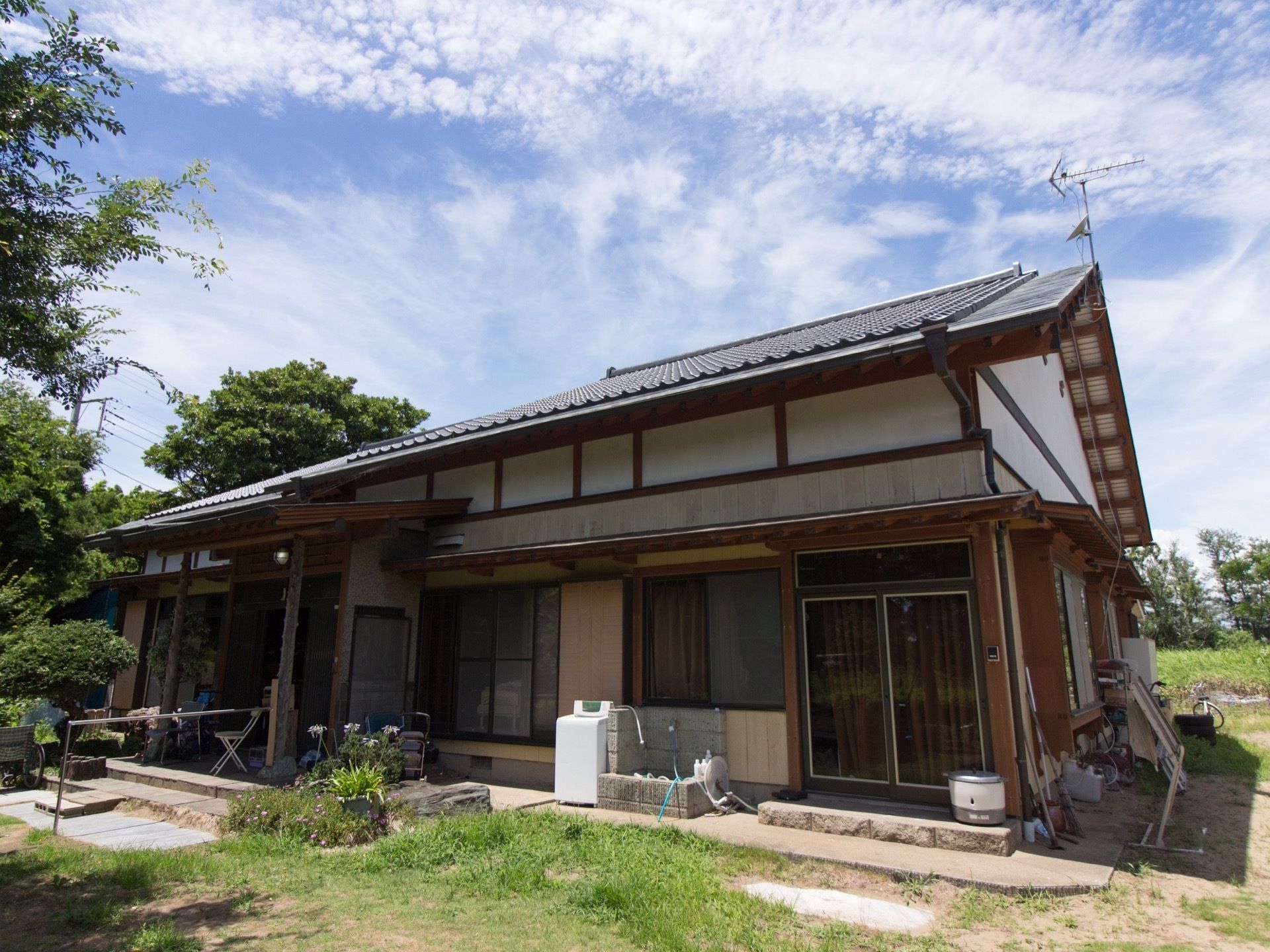瓦屋根のに本格は平屋建てで庭もある。玄関には屋根があり、周りには背の高い建物はない。