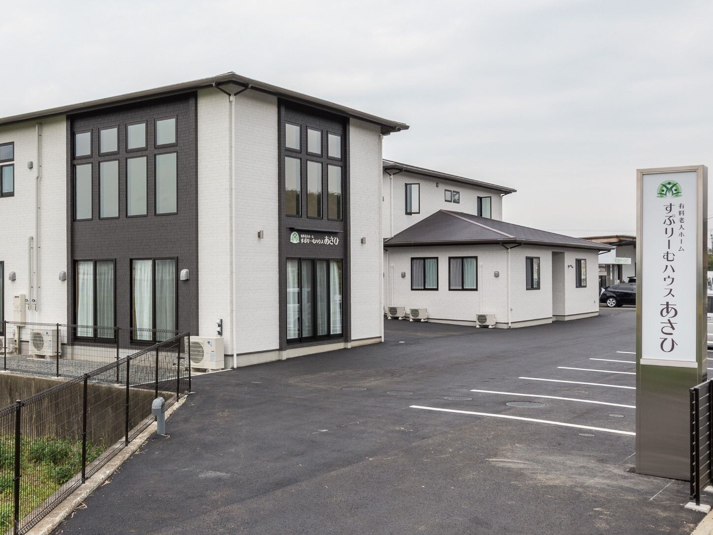 広い敷地内には駐車場があり、モノトーンカラーの2階建ての建物が建っている。敷地の入り口にはホーム名が書かれた看板もある。