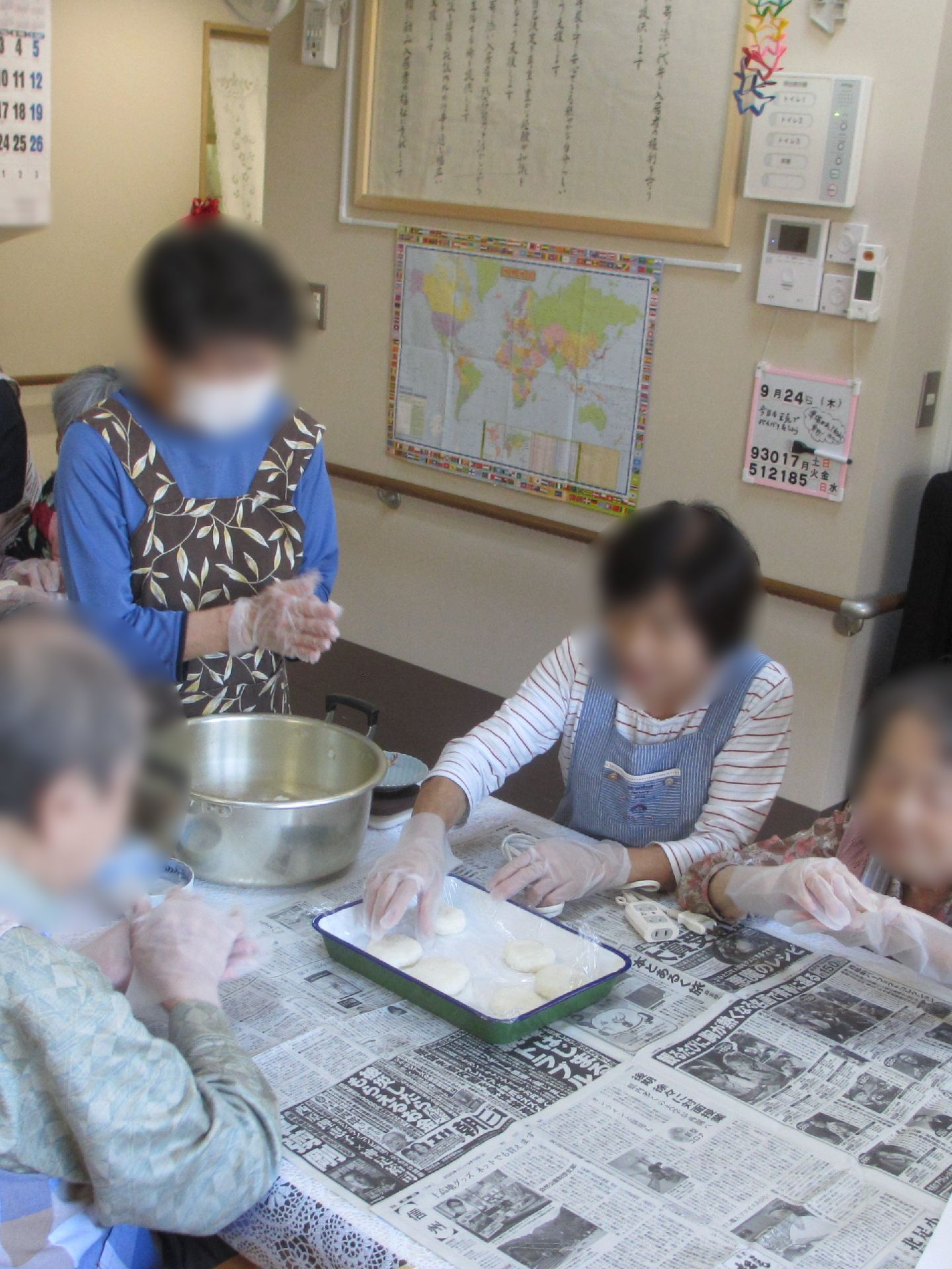 大きな木の下には手入れの行き届いた畑があり、帽子をかぶった数名の人が作業に当たっている。木の後ろには和風の民家が見える。