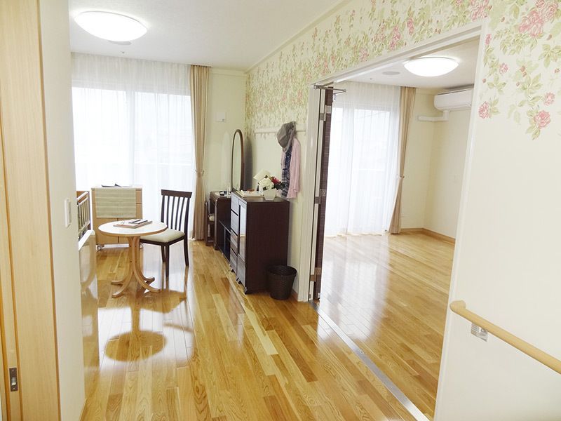 フローリング居室は二部屋続きとなっていて、部屋にはタンスやテーブルセットなどが置かれている。