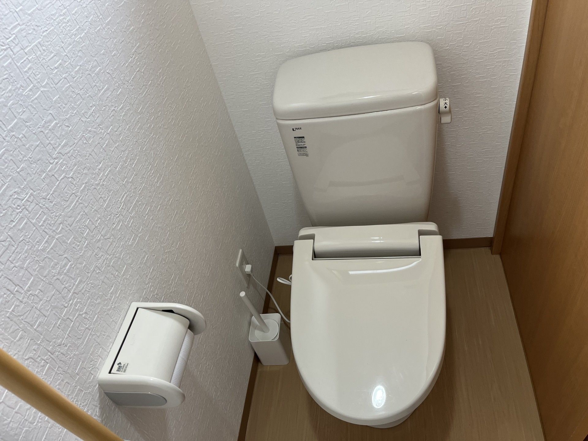 シンプルなトイレ、トイレブラシが床に置かれている
