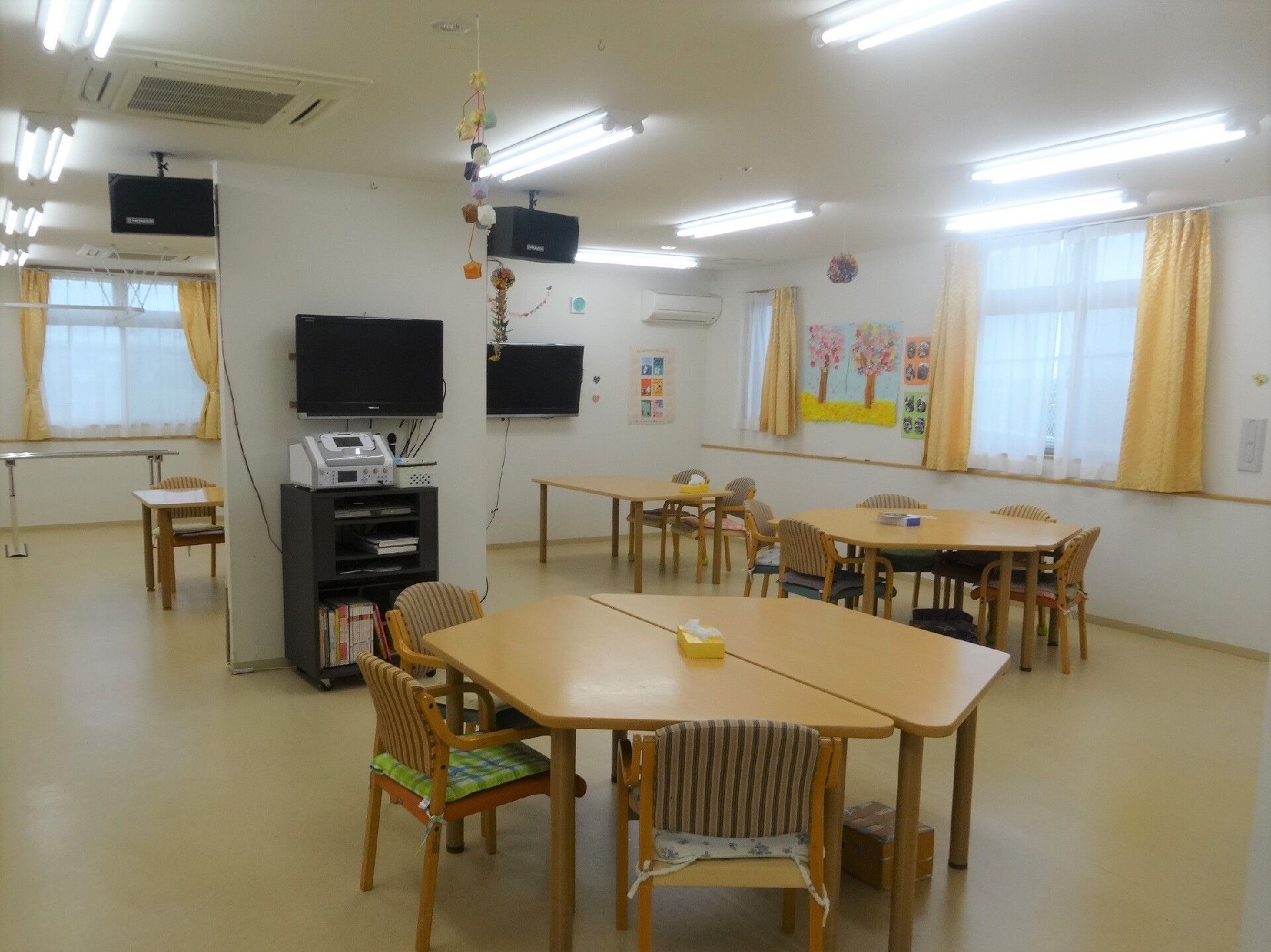 日当たりのいい芝生の上でおしゃべりをしている高齢の夫婦と若い女性スタッフ。