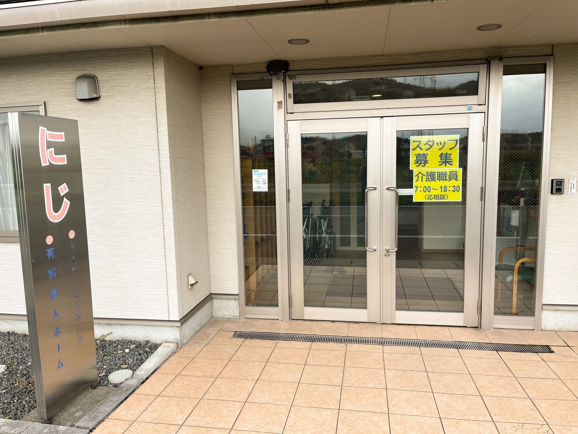スタッフ募集と書かれた張り紙が玄関ドアに張り出されている
