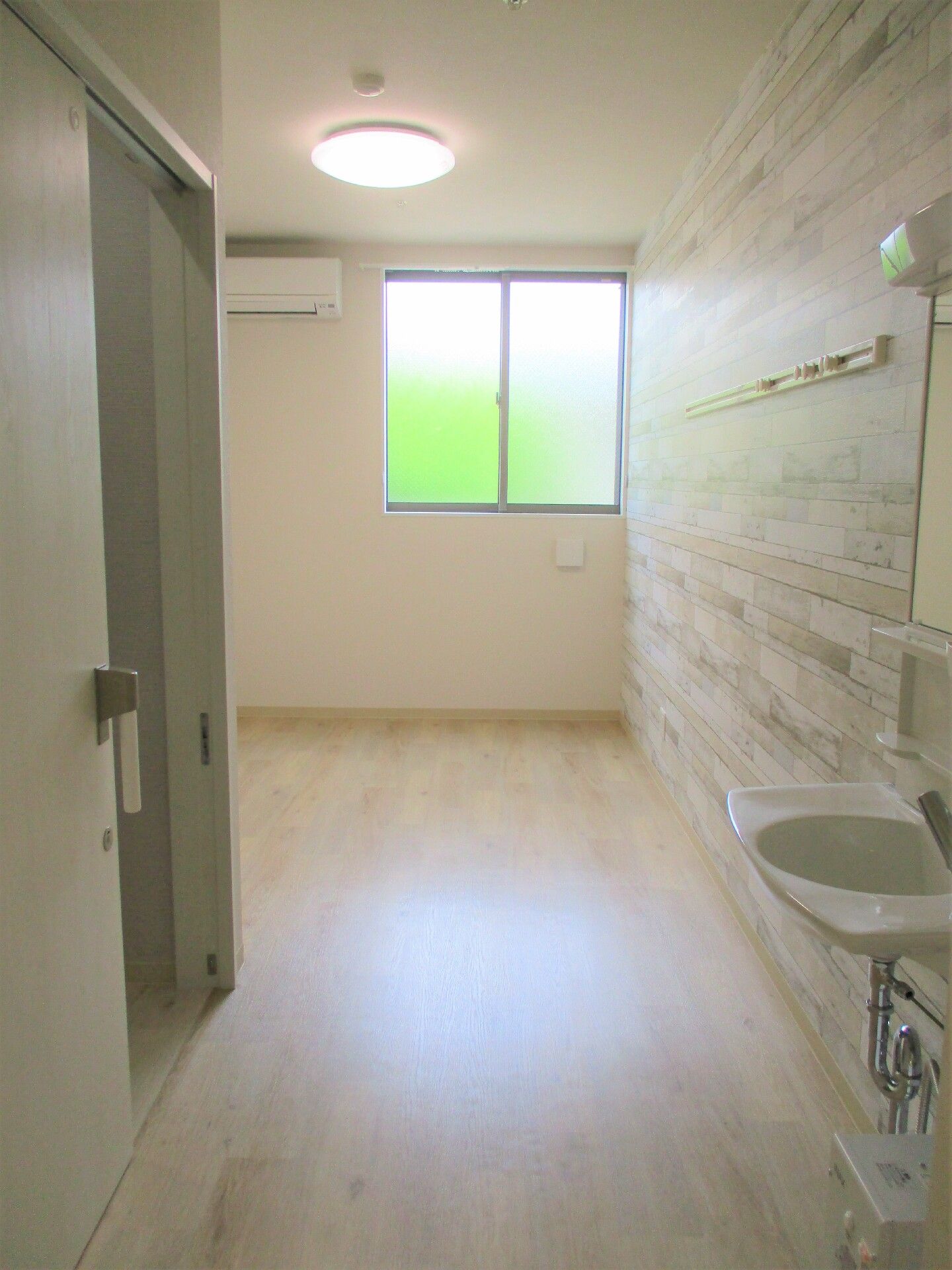 洗面台やトイレを備えた個室の部屋。窓やエアコンも完備されている。