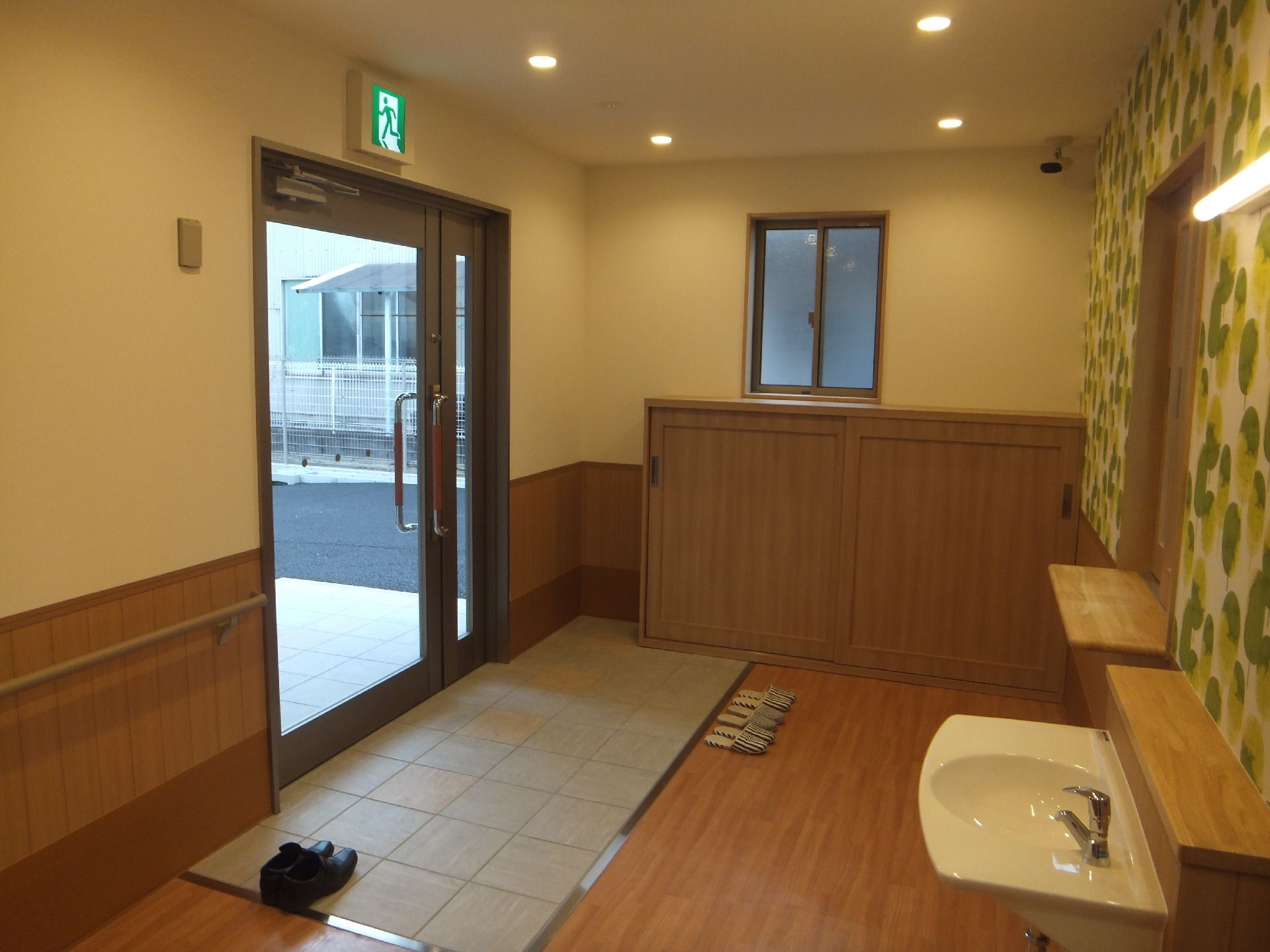 自然が広がる場所で車いすに乗りリラックスする女性とスタッフ。カメラに笑顔を向けている様子