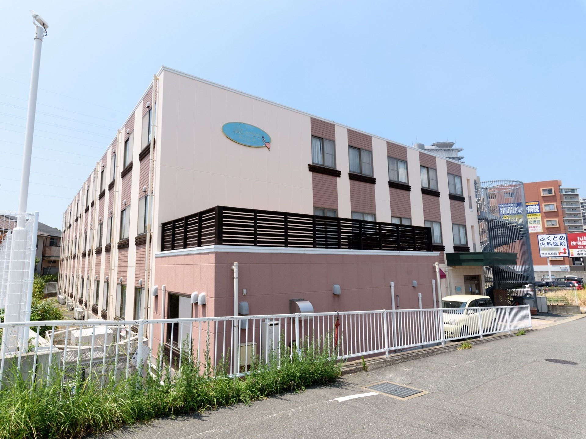 施設の外壁は落ち着いたベージュ色になっている。非常時に上階から降りる際に使う外階段が設けられている。