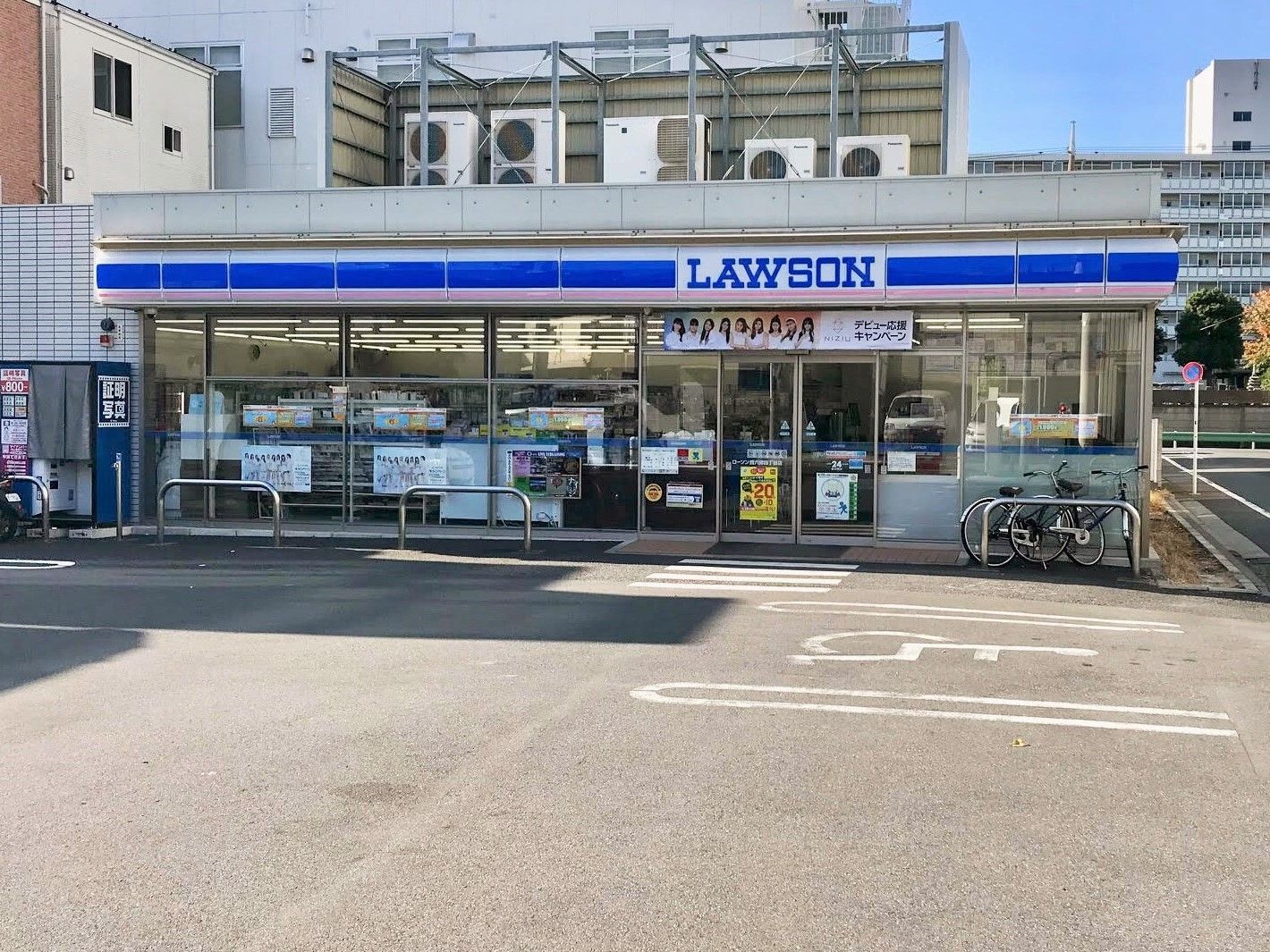 車いすマークがついた駐車場があるローソンがあり、建物の前には自転車が止められている。