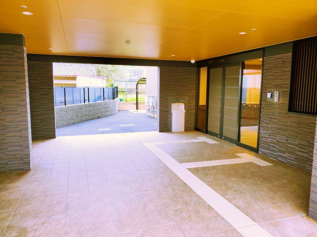 壁面はレンガ調、天井は黄色で塗られたデザインの広い玄関ポーチ