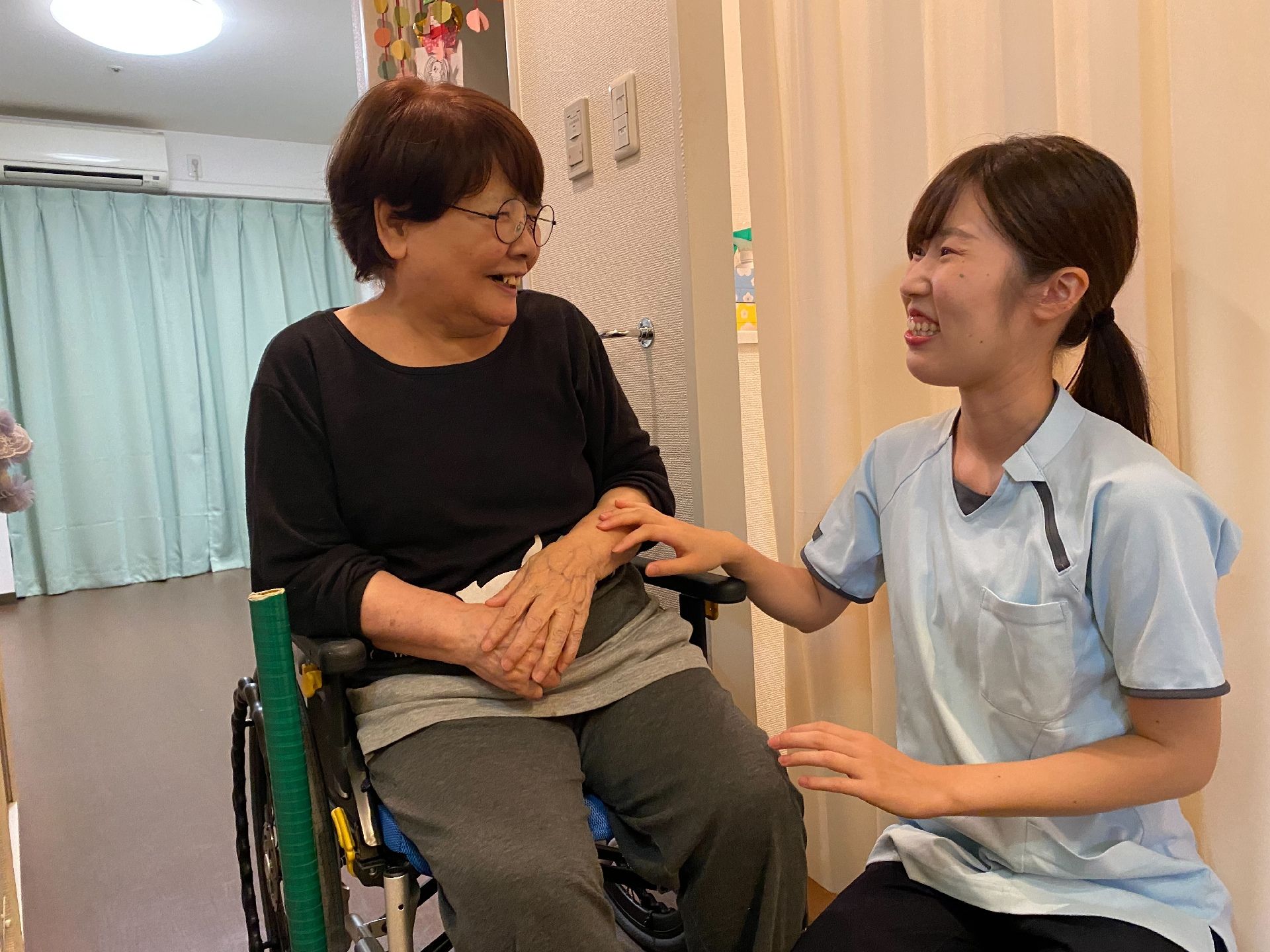 器具を使ってリハビリをする高齢女性と指導する理学療法士の男性