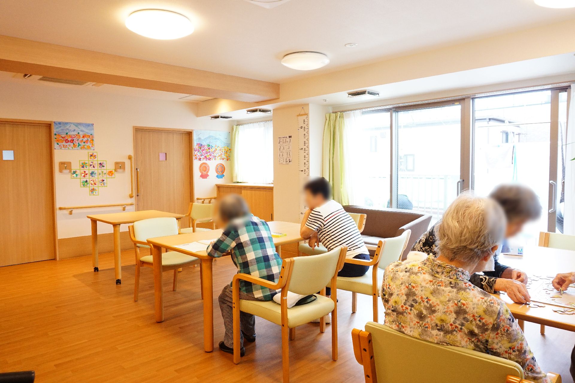 大きな窓から光が入り、入居者が自由に時間を過ごしているリビング