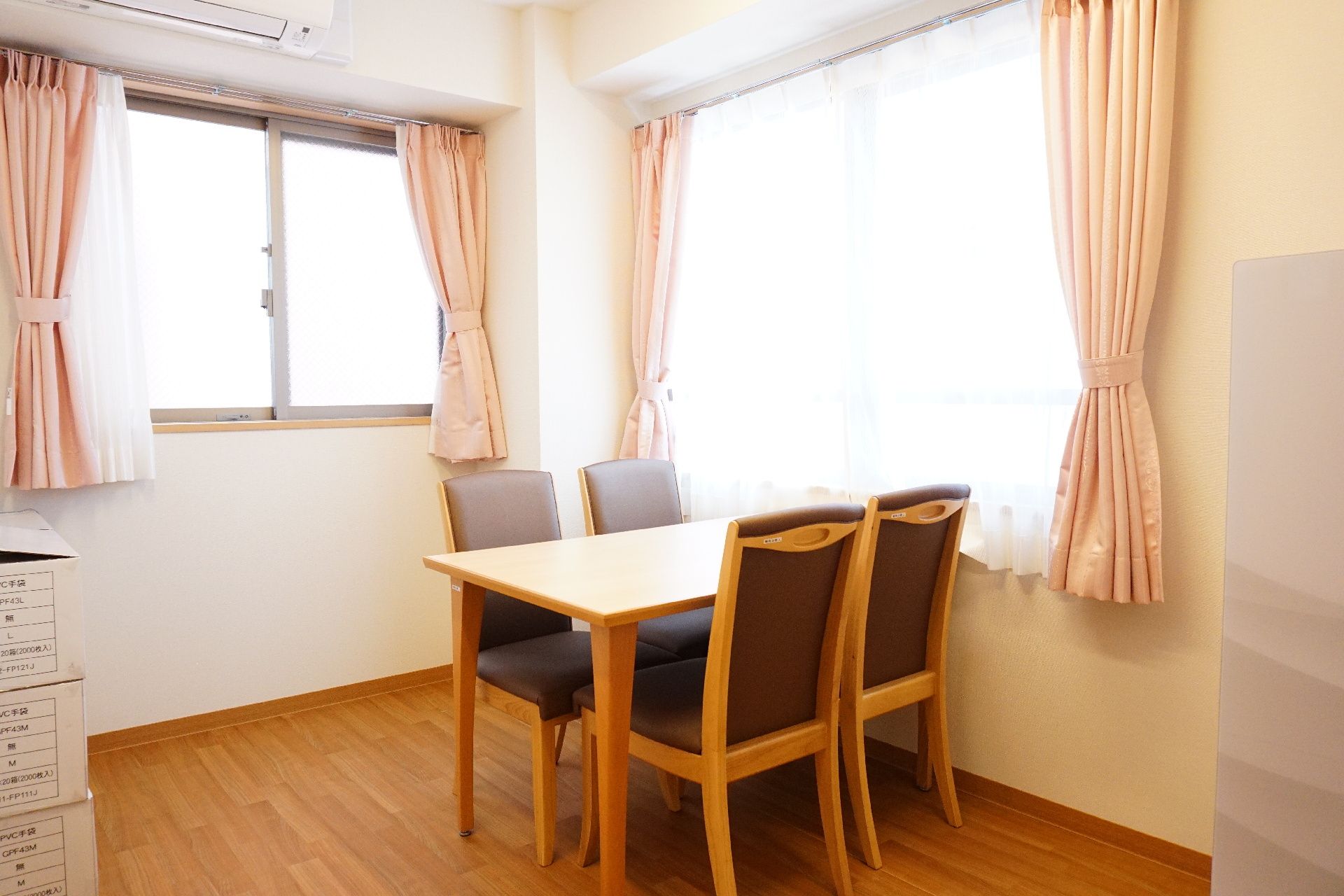 テーブルを挟んで椅子が置かれ、窓から光が入っている部屋