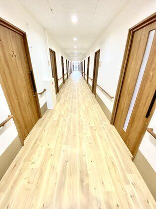 手すりがついた廊下の様子。両側に個室のドアがある廊下の全景