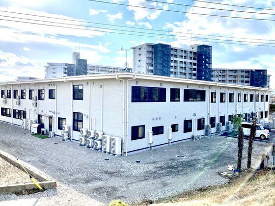 ホワイト基調の背の低い介護施設の様子。エル字型に伸びる建物の全景