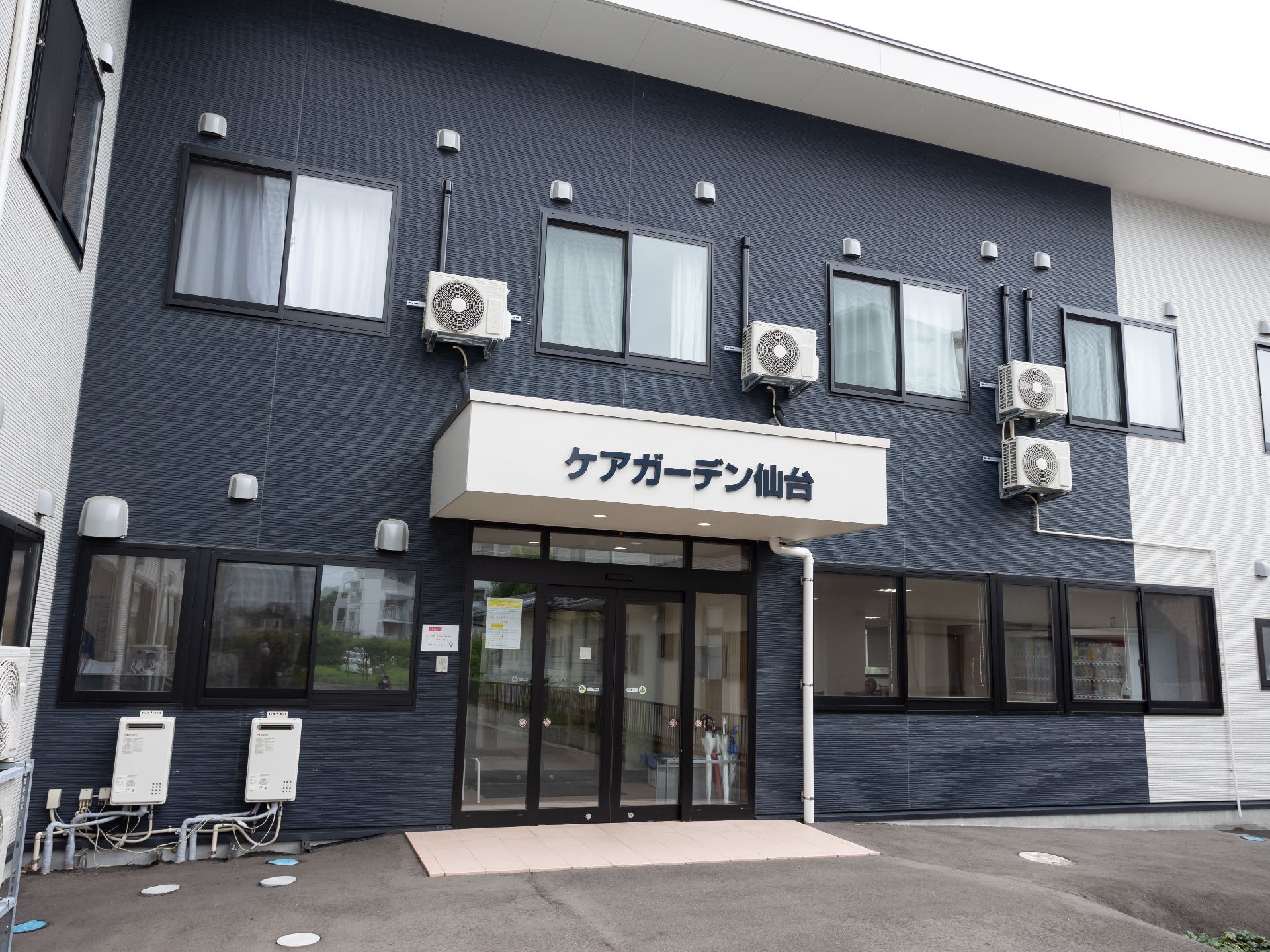 介護車両の前にいる高齢の男女と介助をするヘルパー