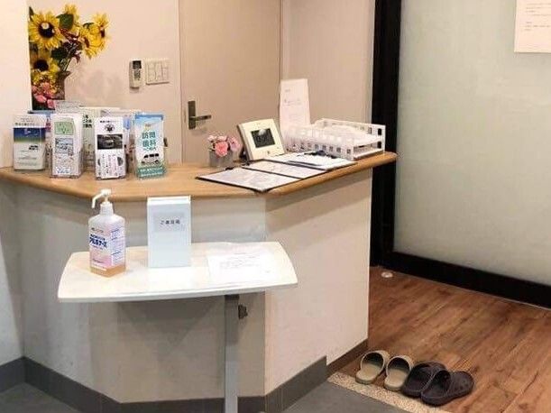 たくさんの消毒液などが並べられた受付には来客用の名簿帳もあり、スリッパも並んでいる。