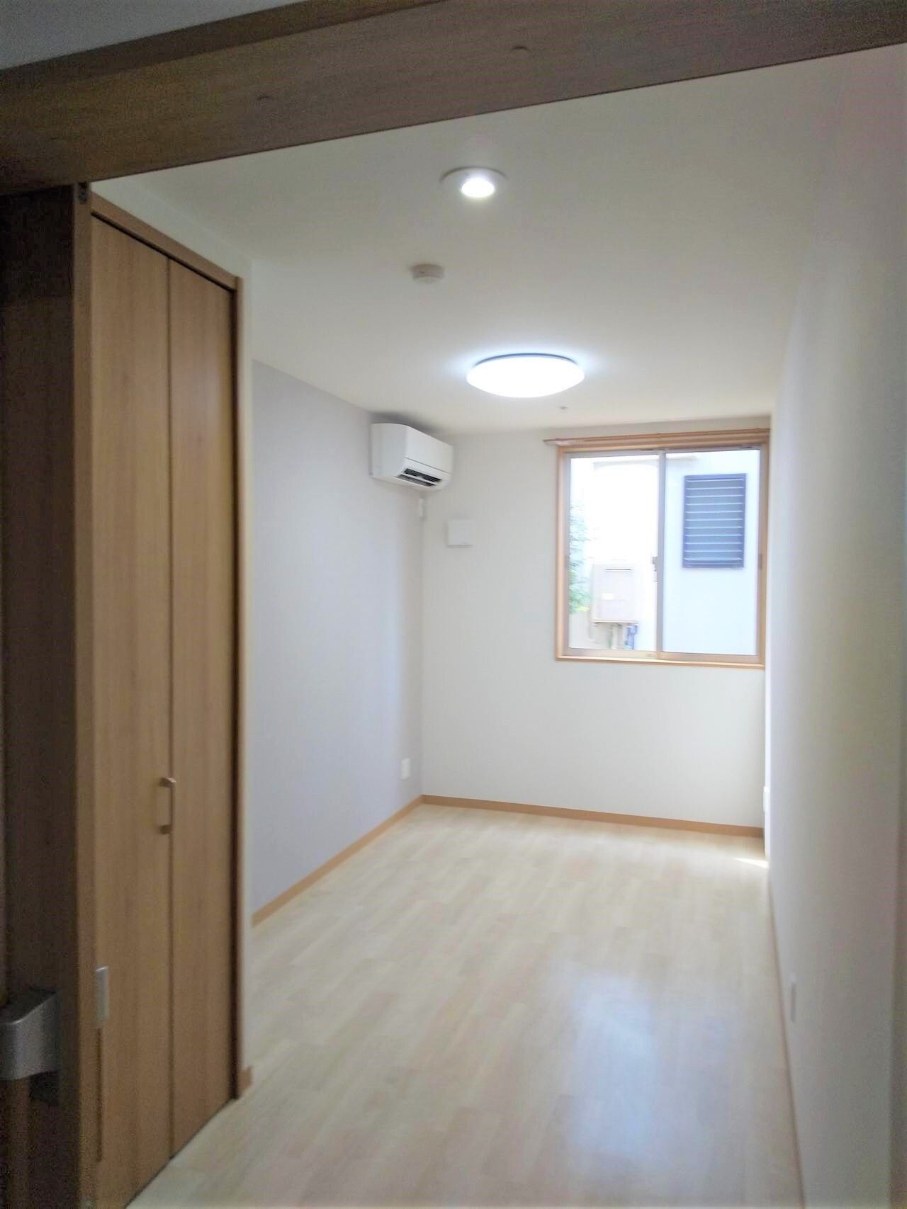 入居者の私物が持ち込まれる前の居室。フローリングの部屋には大き目のクローゼットとエアコン、カーテンのついていない窓がある。