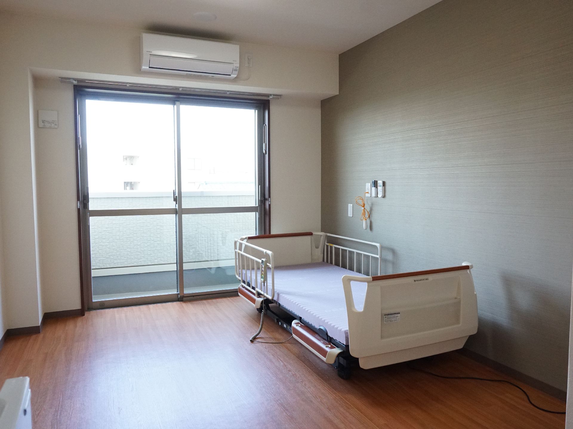 介護ベッドが設置され、大きな窓から日の光が入っている居室