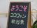 ピンク、緑、黄色のチョークで歓迎の挨拶文が書かれた黒板型の看板