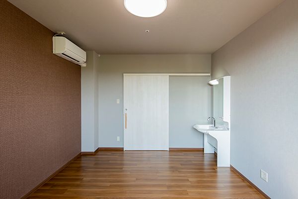 車いす対応の洗面所が付いた部屋はフローリングでエアコンが付き、居室のドアはスライド式。