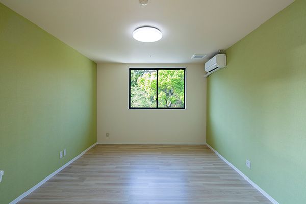エアコン付きのフローリングの部屋にはエアコンやカーテンが付いていない窓などがあり、家具は置かれていない。