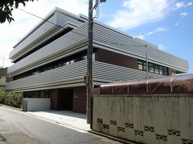 車いすの男性入居者とエプロン姿の女性スタッフが屋外での散歩を楽しんでいる。